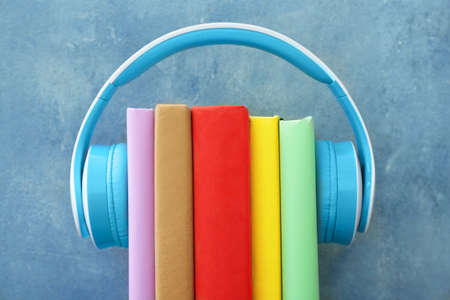 Books and modern headphones on color background. Concept of audiobookの写真素材