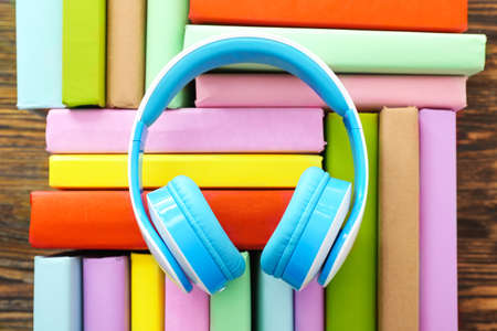 Books and modern headphones on wooden background. Concept of audiobookの写真素材