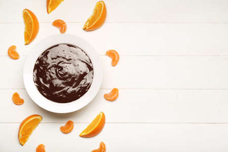 Bowl with tasty chocolate fondue and citrus fruits on white tableの写真素材