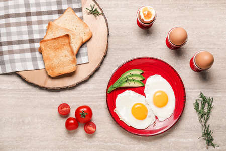 Plate with fried eggs, vegetables and toasted bread on tableの写真素材