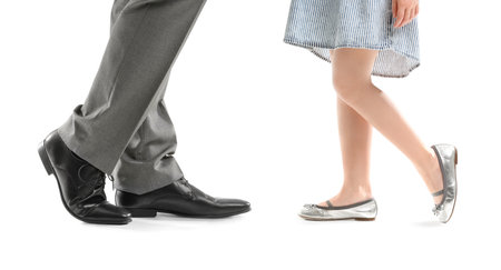 Legs of father and his little daughter dancing against white backgroundの写真素材