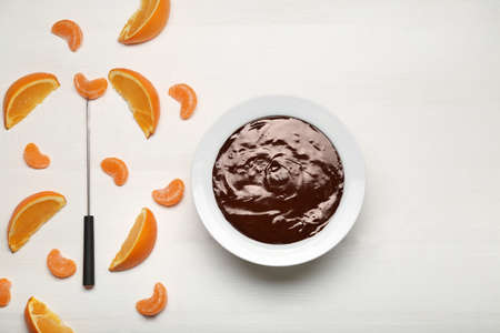 Bowl with tasty chocolate fondue and citrus fruits on white tableの写真素材