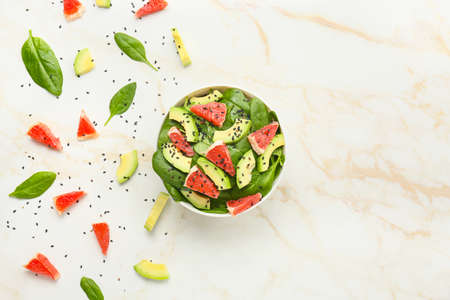 Bowl with tasty salad and ingredients on light background
