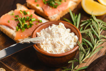 Bowl with tasty cream cheese and sandwiches on board, closeupの写真素材