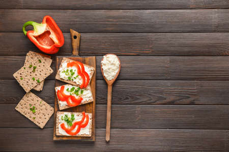 Crispbread with tasty cream cheese and vegetables on tableの写真素材