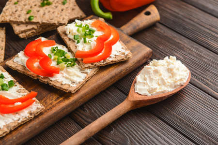 Crispbread with tasty cream cheese and vegetables on table