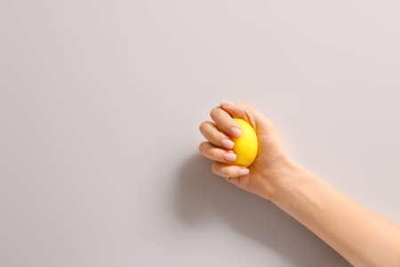 Hand squeezing stress ball on light backgroundの写真素材