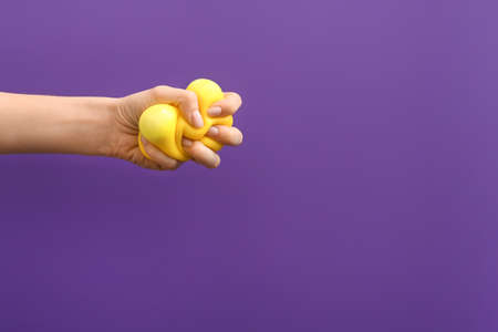 Hand squeezing stress ball on color backgroundの写真素材