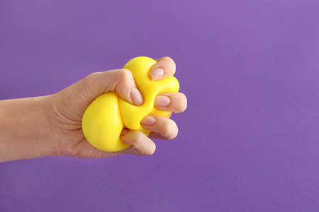 Hand squeezing stress ball on color backgroundの写真素材