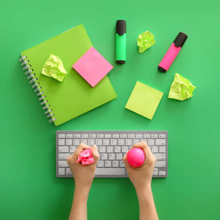 Woman squeezing stress ball while working on PC, top view