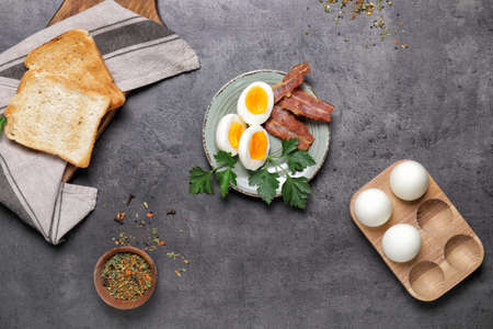 Plate with boiled eggs, bacon and toasted bread on dark backgroundの写真素材