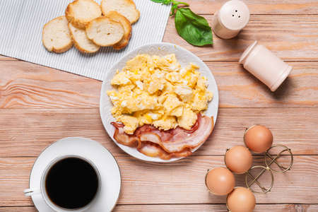 Plate with scrambled egg and bacon on tableの写真素材