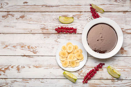 Bowl with tasty chocolate fondue and fruits on tableの写真素材