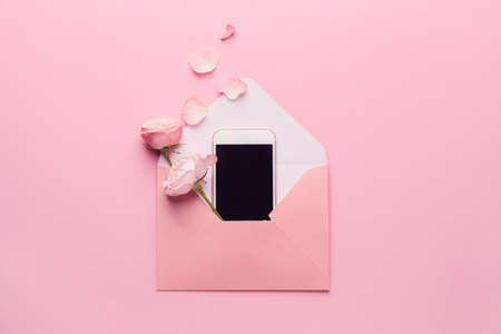 Composition with envelope, mobile phone and flowers on pink backgroundの写真素材