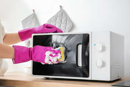 Woman cleaning microwave oven in kitchen