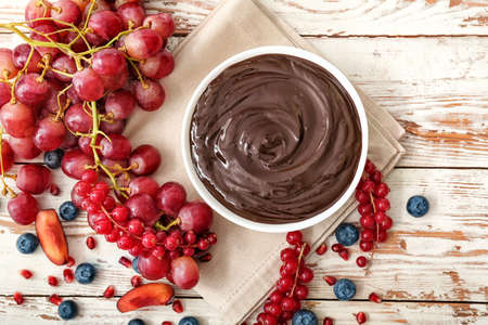 Bowl with tasty chocolate fondue and berries on tableの写真素材