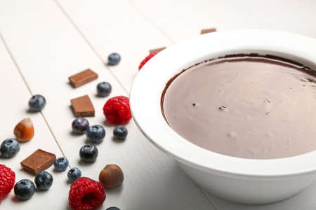 Bowl with tasty chocolate fondue and berries on tableの写真素材
