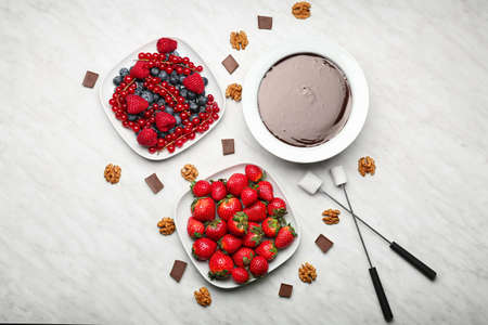 Bowl with tasty chocolate fondue, berries and marshmallow on tableの写真素材