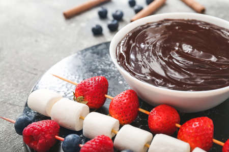Bowl with tasty chocolate fondue, berries and marshmallow on tableの写真素材