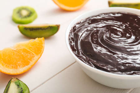 Bowl with tasty chocolate fondue and fruits on table, closeupの写真素材