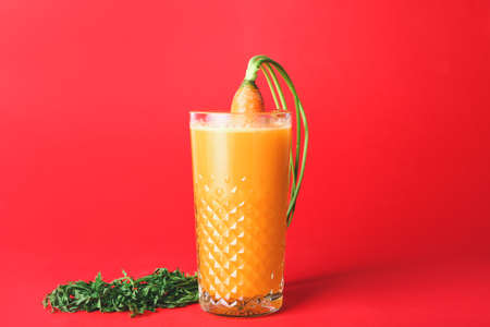 Glass of fresh carrot juice on color backgroundの写真素材