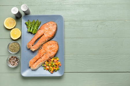 Plate with fried salmon and vegetables on tableの写真素材