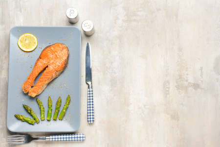 Plate with fried salmon and asparagus on tableの写真素材