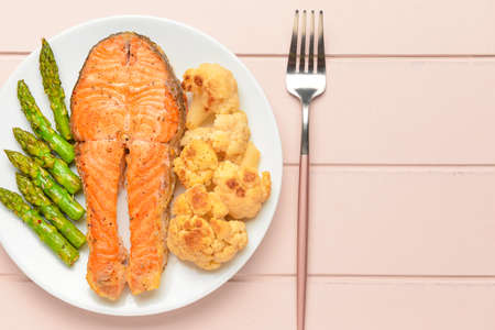 Plate with fried salmon and vegetables on tableの写真素材