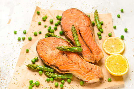 Tasty fried salmon with vegetables on tableの写真素材