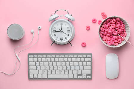 Computer keyboard with mouse, alarm clock and cornflakes on pink backgroundの写真素材