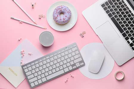 Modern devices with stationery and donut on pink backgroundの写真素材