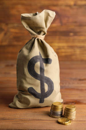 Bag with money and coins on wooden backgroundの写真素材
