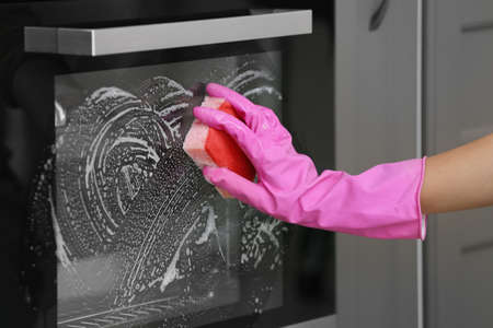 Woman cleaning oven in kitchenの写真素材