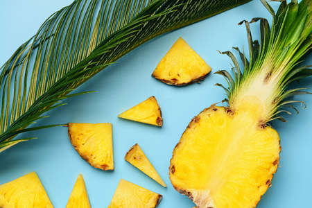 Fresh cut pineapple and palm leaf on color background