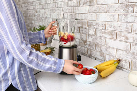 Woman preparing tasty milkshake at home