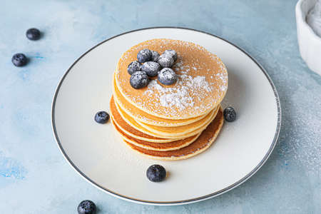 Plate with stack of tasty pancakes on table
