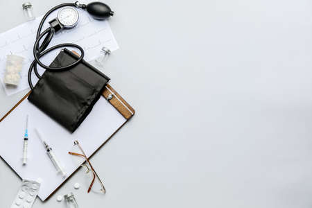 Composition with sphygmomanometer, clipboard and pills on light backgroundの写真素材
