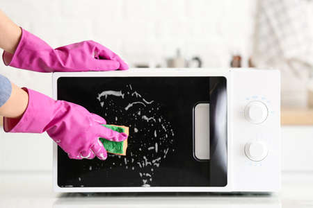 Woman cleaning microwave oven in kitchenの写真素材