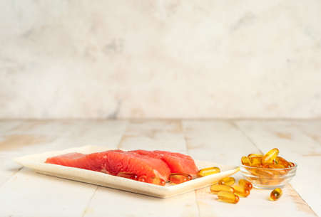 Plate with fish and oil pills on white tableの写真素材