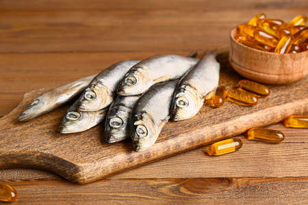 Fish with oil pills on wooden background