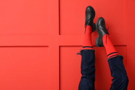Legs of young woman in socks, shoes and jeans on color backgroundの写真素材