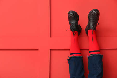 Legs of young woman in socks, shoes and jeans on color backgroundの写真素材
