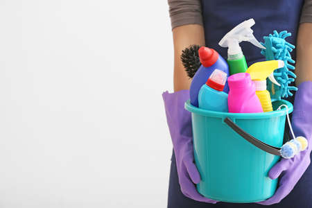 Janitor with set of cleaning supplies on light backgroundの写真素材