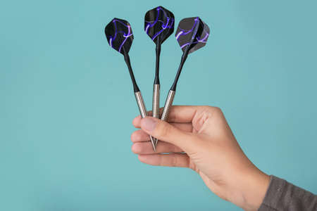 Female hand with darts on color background