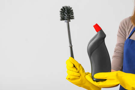 Janitor with detergent and toilet brush on light background
