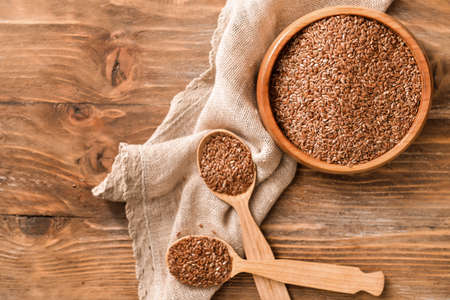 Bowl with flax seeds and spoons on wooden backgroundの写真素材