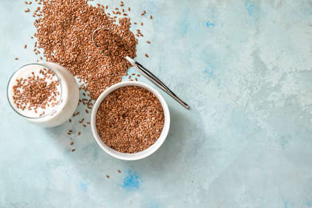 Bowl with flax seeds and glass of yogurt on color backgroundの写真素材