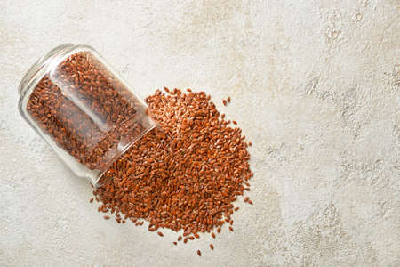 Overturned jar with flax seeds on light backgroundの写真素材