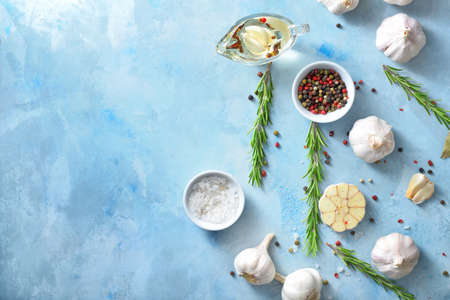 Fresh garlic with spices, oil and herbs on color backgroundの写真素材