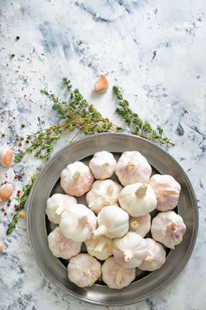 Plate with fresh garlic and herbs on white background